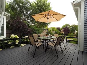 a table with chairs and an umbrella on a deck at Blue Skies Bed & Breakfast in Niagara on the Lake