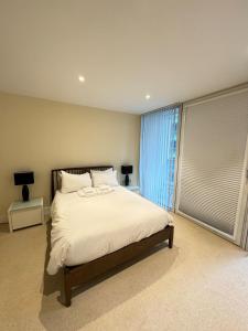 a bedroom with a bed and a large window at Contemporary 2BD Flat wBalcony Canary Wharf! in London