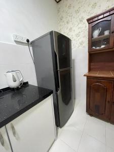 Il comprend une cuisine équipée d'un réfrigérateur noir et d'un comptoir. dans l'établissement THREE ROOMS WITH WIFI HOMESTAY D’RAZAK IN KUALA TERENGGANU, à Kuala Terengganu