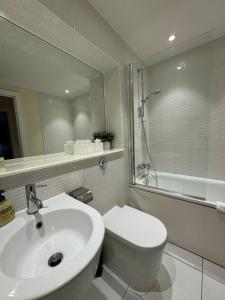 a bathroom with a sink and a toilet and a mirror at Contemporary 2BD Flat wBalcony Canary Wharf! in London