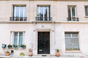 een wit gebouw met een zwarte deur en potplanten bij Chic Studio Apartment for 3 - La Villette! in Parijs
