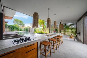 eine Küche mit einer Theke mit Hockern und einer Arbeitsplatte in der Unterkunft Villa Lennon - Tropical 3 Bedroom Villa Facing The Rice fields in Canggu