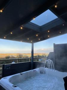 a bath tub with a large window with a view at terfyn hall holiday apartment 3 stargazer in Prestatyn
