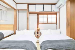 a bedroom with two beds and a window at Takii Motomachi Irodori House in Osaka