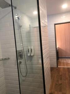 um chuveiro com uma porta de vidro na casa de banho em โรงแรม เดอะโมเดล การ์เด้น em Yasothon