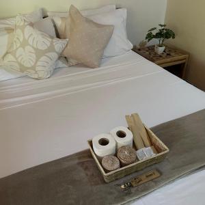 uma bandeja com três rolos de papel higiénico numa cama em Hidden of Cailan Extension Transient House em El Nido