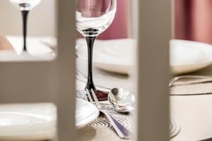 un tavolo con bicchiere di vino, piatti e cucchiai di Sika DeLuxe Apartment a Arad