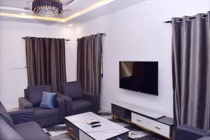 sala de estar con 2 sillas y TV de pantalla plana en Les 9 Plurielles T 2 KPALIME KOUMA KONDA, en Palimé