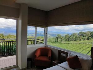 a room with a bed and a chair and a window at Gee Resort & Heights in Idukki