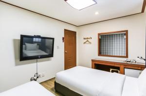 a bedroom with a bed and a flat screen tv at Nokwon Motel in Jeju