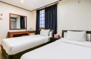two beds in a hotel room with a mirror at Nokwon Motel in Jeju
