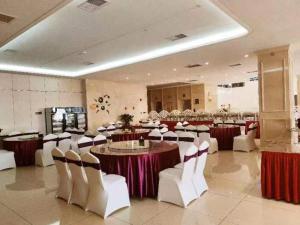 Huayin的住宿－华山欣源国际酒店，一个带桌子和白色椅子的大型宴会厅