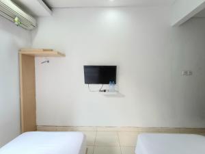um quarto com duas camas e uma televisão na parede em Urbanview Hotel B Liv Kendari em Puunggolaka