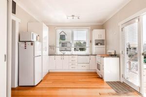 eine Küche mit weißen Schränken und einem weißen Kühlschrank in der Unterkunft Rose Cottage in Devonport