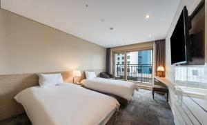 ein Hotelzimmer mit 2 Betten und einem Flachbild-TV in der Unterkunft The Best Jeju Seongsan in Seogwipo