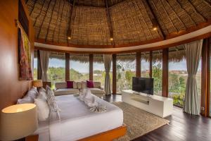 Un dormitorio con una cama y un televisor en una habitación. en Dayu Mirah Resort, en Jimbaran