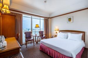 a hotel room with a bed and a table and chairs at V.L. Hatyai Hotel in Hat Yai