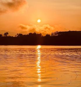 una puesta de sol sobre un cuerpo de agua con la puesta de sol en พาราไดซ์รีสอร์ต สังขละบุรี Paradise Resort at Sangkhlaburi en Sangkhla Buri