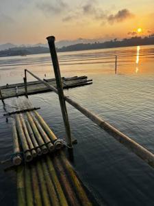 三克拉布里的住宿－พาราไดซ์รีสอร์ต สังขละบุรี Paradise Resort at Sangkhlaburi，水面上的木头码头,背景是日落