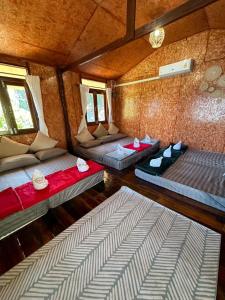 a room with two beds and two windows at พาราไดซ์รีสอร์ต สังขละบุรี Paradise Resort at Sangkhlaburi in Sangkhla Buri