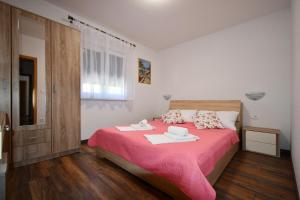 una camera con un letto e una coperta rosa di Apartmani Kičuda a Banjol
