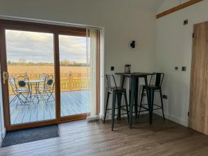 a room with a table and chairs and a balcony at Brooke View Barns No 1 in Norwich