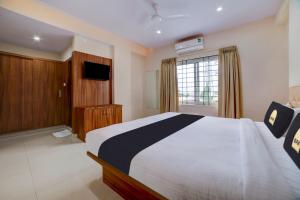 a bedroom with a large bed and a television at Townhouse OAK Ess Jay in Bangalore