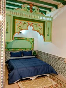 a bedroom with a blue bed with an ornate headboard at Dar Baaziz 3 in Sousse