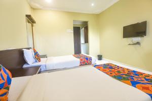 Cette chambre comprend 2 lits et une télévision à écran plat. dans l'établissement FabExpress Sunrise By Vihasta, à Madgaon