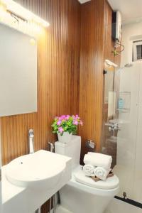 baño con aseo, lavabo y flores en Căn hộ 2PN, 2WC tầng 25 2 bedrooms luxury apartment, en Ho Chi Minh