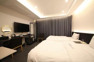 Habitación de hotel con 2 camas, escritorio y TV. en The M Hotel en Jeju