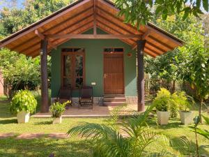 a small green house with a wooden pergola at suncity privacy cottages in Udawalawe