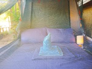 Una cama en una tienda con una estatuilla. en BH Beachfront Mini Glamping Tent, en El Nido
