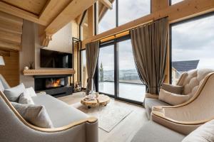 a living room with a fireplace and large windows at Chaletovo Mountain Residences in Zakopane