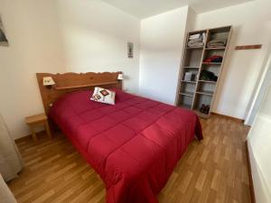 1 dormitorio con cama roja y estante para libros en AU PIED DES PISTES D'ARVIEUX en Arvieux