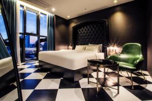 a bedroom with a bed and a green chair at Hotel The Designers Premier Kondae in Seoul