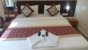 una camera d'albergo con un letto con due telecomandi sopra di HOTEL SJ PRIDE INN a Bhubaneshwar