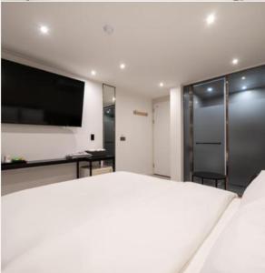 1 dormitorio con 1 cama blanca grande y TV de pantalla plana en Baron De Hotel en Seúl