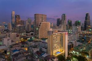 Hilton Garden Inn Bangkok Silom في بانكوك: أفق المدينة في الليل مع المباني المضاءة