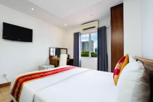 a bedroom with a white bed and a television at King Hotel Saigon Airport in Ho Chi Minh City
