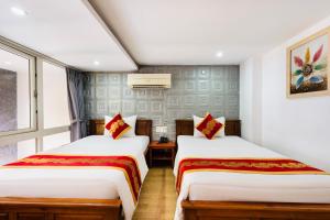 two beds in a room with white walls at King Hotel Saigon Airport in Ho Chi Minh City