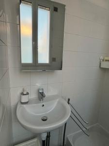 ein weißes Badezimmer mit einem Waschbecken und einem Spiegel in der Unterkunft Studio à 7 min du métro Le Kremlin-Bicêtre - proche Paris in Villejuif