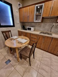 a kitchen with a wooden table and chairs and a microwave at شقق نبراس الفارس للشقق المخدومة - اقتصادي in Tabuk