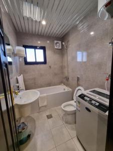 a bathroom with a tub and a sink and a toilet at شقق نبراس الفارس للشقق المخدومة - اقتصادي in Tabuk