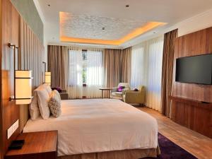 a hotel room with a large bed and a flat screen tv at Vivanta Tawang in Tawang