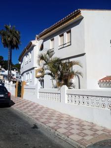 a white house with a white fence and palm trees at Studio mit Meerblick und Nähe zum Strand, WLAN in Torremolinos