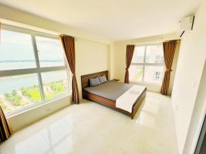 a bedroom with a bed and two large windows at GRAD 1989's Homes Halong in Ha Long