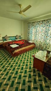 a bedroom with a bed and a ceiling fan at Tip Top Pahalgam in Pahalgām
