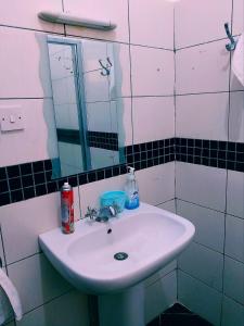 La salle de bains est pourvue d'un lavabo blanc et d'un miroir. dans l'établissement Bree Airbnb, à Malindi