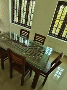 a glass dining room table with chairs and a glass top at Munroe La Casa in Kollam